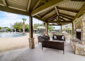 Thumbnail 37 of 42 - a covered patio with a fireplace and seating next to a pool