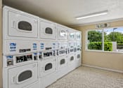 Thumbnail 13 of 26 - A laundry room with a row of washers and dryers.