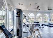 Thumbnail 24 of 35 - A gym with treadmills, elliptical machines, and a fan.
