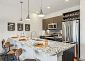 Thumbnail 5 of 49 - A kitchen with a marble countertop and a refrigerator.