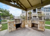 Thumbnail 35 of 42 - an outdoor kitchen with two bbq grills and a pergola