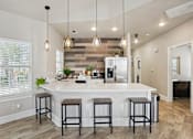 Thumbnail 44 of 70 - A kitchen with a white island and bar stools.