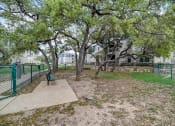 Thumbnail 40 of 42 - a park with trees and a bench in front of a building
