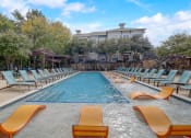 Thumbnail 38 of 50 - a swimming pool with chairs and a building in the background