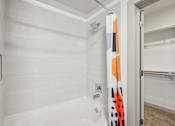 Thumbnail 15 of 49 - A white bathroom with a white tub and a white shower.