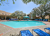 Thumbnail 35 of 45 - A pool surrounded by sun loungers and trees.