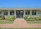 Thumbnail 7 of 25 - A building with a grey roof and a brick pathway leading to the entrance.