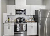 Thumbnail 1 of 36 - A modern kitchen with a stainless steel refrigerator, microwave, and oven.