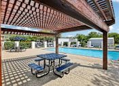 Thumbnail 15 of 26 - A picnic table with a blue top is in the foreground of a pool area.