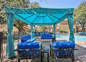 Thumbnail 37 of 45 - A poolside area with blue chairs and a canopy.