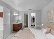 Thumbnail 14 of 37 - a bedroom with a bed and a bathroom with a sink and a mirror