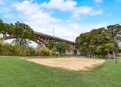 Thumbnail 37 of 44 - a volleyball court in a park with a bridge in the background