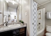 Thumbnail 9 of 15 - A bathroom with a sink, mirror, and shower.