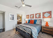 Thumbnail 12 of 49 - A bedroom with a bed, a dresser, and a ceiling fan.