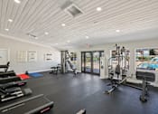 Thumbnail 10 of 25 - A spacious gym with a variety of equipment and a view of the pool outside.