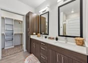 Thumbnail 12 of 54 - A bathroom with a white counter top and brown cabinets.