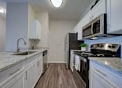 Thumbnail 6 of 17 - a kitchen with white cabinets and a stove and a sink