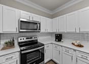 Thumbnail 16 of 52 - a kitchen with white cabinets and black appliances and a microwave