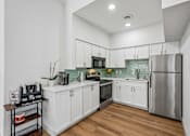 Thumbnail 13 of 33 - A kitchen with white cabinets and a stainless steel refrigerator.