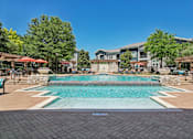 Thumbnail 34 of 55 - A large outdoor swimming pool surrounded by a stone wall and seating areas.