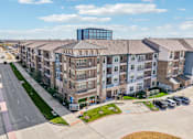 Thumbnail 47 of 49 - A large apartment complex with a parking lot in front.