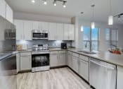 Thumbnail 3 of 44 - an empty kitchen with white cabinets and stainless steel appliances