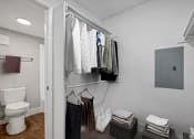 Thumbnail 10 of 41 - a bathroom with a toilet and a closet with clothes hanging on the wall