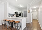 Thumbnail 2 of 70 - A kitchen with white cabinets and a white island with three stools.