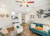 Thumbnail 2 of 27 - A living room with a green couch and a white chair.