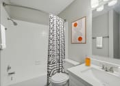 Thumbnail 8 of 28 - a bathroom with a shower curtain and a sink and a toilet