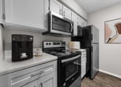 Thumbnail 4 of 29 - a kitchen with black appliances and white cabinets