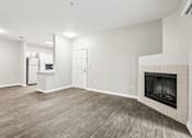 Thumbnail 14 of 48 - A living room with a fireplace and a refrigerator in the corner.