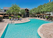 Thumbnail 35 of 55 - A large outdoor swimming pool surrounded by a patio area with chairs and umbrellas.