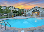 Thumbnail 16 of 22 - A swimming pool in a backyard with a sunset in the background.