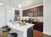 Thumbnail 9 of 33 - an open kitchen with a large white island and wooden cabinets