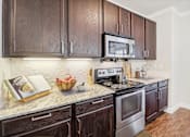Thumbnail 11 of 33 - a kitchen with wooden cabinets and stainless steel appliances