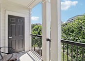 Thumbnail 23 of 33 - a balcony with a black door and a table and a chair