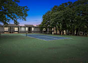 Thumbnail 67 of 79 - a tennis court in front of a building with trees