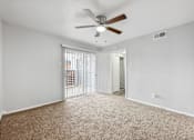 Thumbnail 16 of 79 - an empty living room with a ceiling fan and a door to a balcony