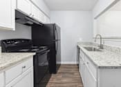 Thumbnail 22 of 79 - an empty kitchen with white cabinets and a black stove and refrigerator