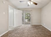 Thumbnail 62 of 79 - an empty living room with a ceiling fan and a door to a balcony
