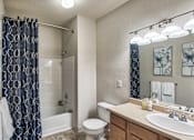 Thumbnail 6 of 22 - A bathroom with a white toilet, a white sink, and a blue shower curtain.