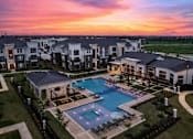 Thumbnail 31 of 31 - A beautiful sunset view of a swimming pool surrounded by apartment buildings.