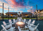 Thumbnail 25 of 28 - a fire pit with white rocking chairs and string lights
