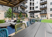 Thumbnail 13 of 31 - a patio with a table and chairs in front of an apartment building