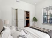 Thumbnail 7 of 28 - a bedroom with a large bed and a door to a bathroom