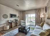 Thumbnail 2 of 22 - A living room with a white couch and a television on the wall.