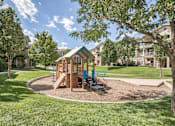 Thumbnail 20 of 22 - A playground with a wooden swing set and blue chairs.