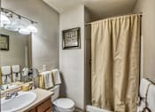 Thumbnail 7 of 22 - A bathroom with a sink, toilet, and shower curtain.