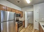 Thumbnail 1 of 22 - A kitchen with a stainless steel refrigerator, microwave, oven, and wooden cabinets.